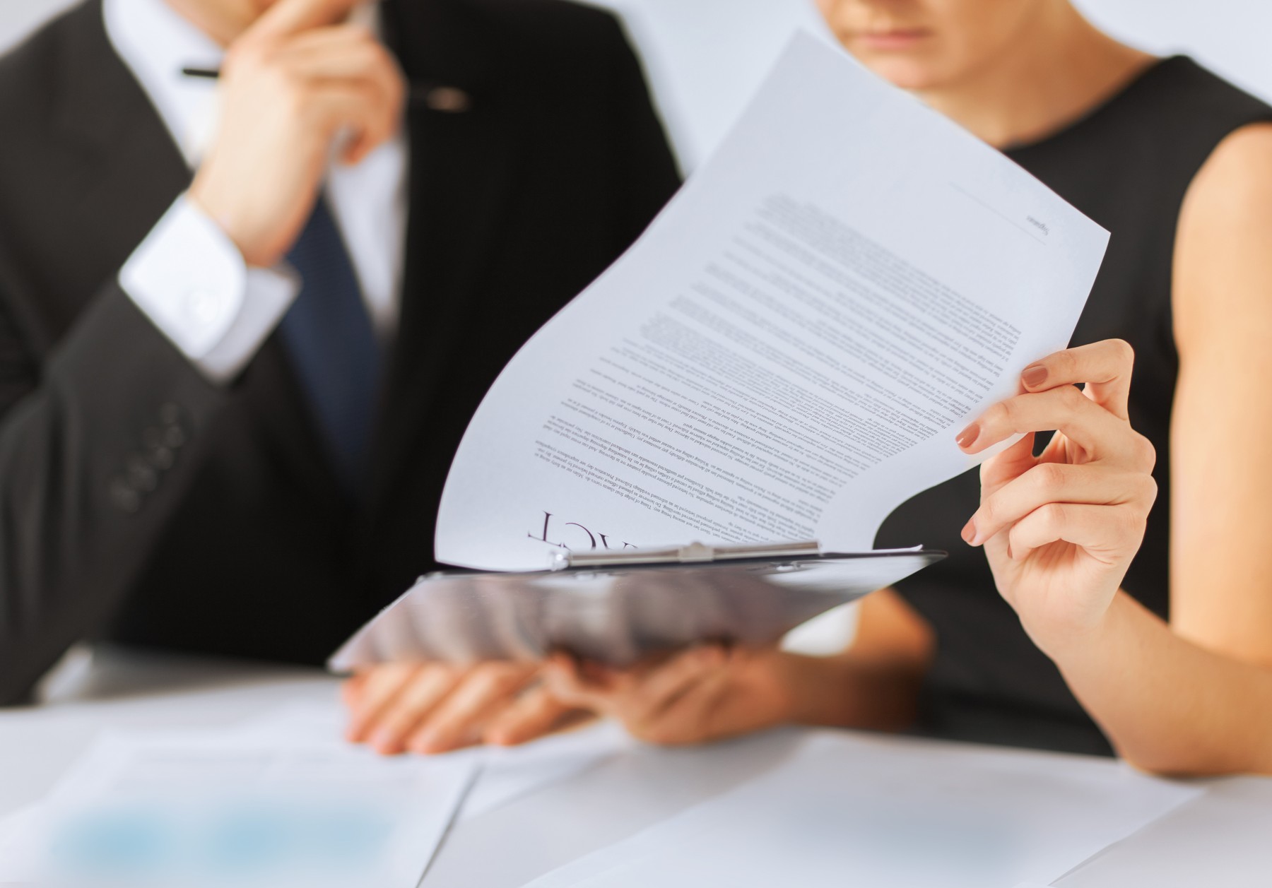 Hands holding a printed document above a clipboard on a table